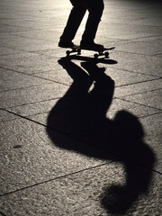 Fototapeta na wymiar skater jumping on his skateboard with his shadow in evening backlight
