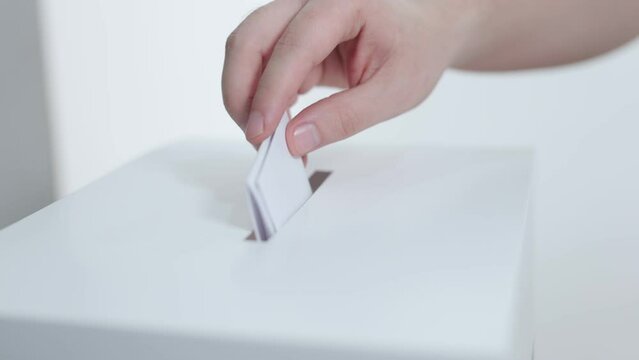 close up of a hand of a person putting his vote in a ballot box. Democratic elections day