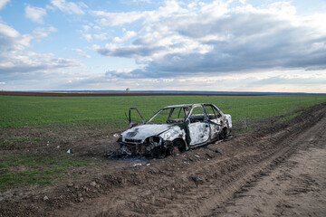 A burned out car. Burnt car in the field. Car fire, vehicle fire due to short circuit. Stolen car...