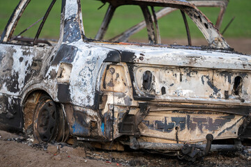 A burned out car. Burnt car in the field. Car fire, vehicle fire due to short circuit. Stolen car...