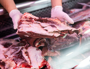 Close-up in hands of seller is large piece slice T-bone. Wide range of meat farm store, Assorted...