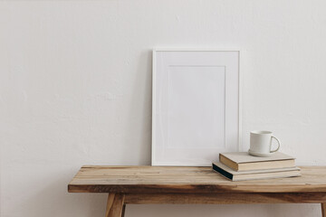 Vertical white picture frame, poster mockup on vintage wooden bench, table. Cup of coffee, tea on...