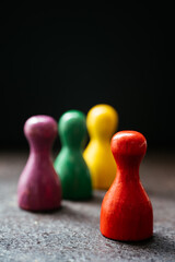 Three pawn-style playing pieces standing together and a red one in a distance from them