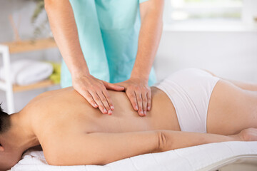 Obraz na płótnie Canvas Male massage therapist massaging back of adult female patient in office