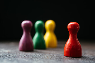 Three pawn-style playing pieces standing together and a red one in a distance from them