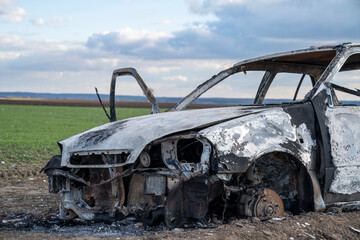 A burned out car. Burnt car in the field. Car fire, vehicle fire due to short circuit. Stolen car...