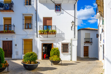An open door to a shop in a small plaza in the hillside white village of Grazalema, Spain, in the Cadiz Province of Andalusia Spain. - obrazy, fototapety, plakaty