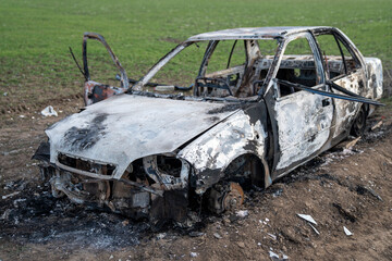 A burned out car. Burnt car in the field. Car fire, vehicle fire due to short circuit. Stolen car...