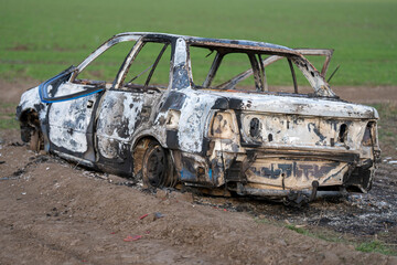 A burned out car. Burnt car in the field. Car fire, vehicle fire due to short circuit. Stolen car...