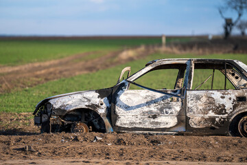 A burned out car. Burnt car in the field. Car fire, vehicle fire due to short circuit. Stolen car intentional arson. One vehicle was damaged in the fire. - obrazy, fototapety, plakaty