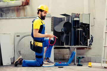 Skilled technician commissioned for routine air conditioner maintenance, assembling manometer...