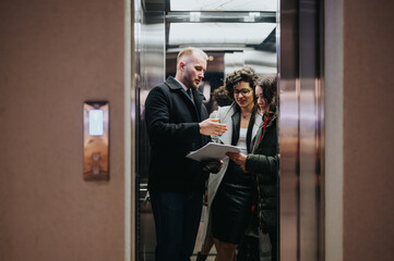 Professional business team discussing work in office elevator space.