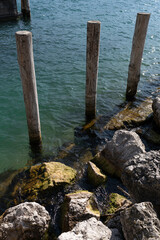 mooring posts on the embankment of a clear lake on a sunny day and mountains in the background