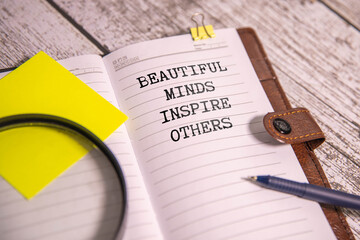 Hand with marker writing the word Beautiful Minds Inspire Others