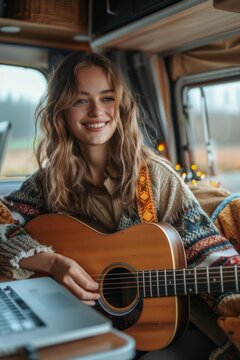 Smiling young woman playing acoustic guitar inside cozy camper van