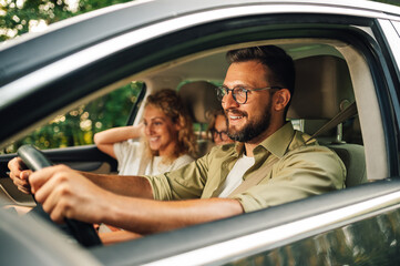 Father driving a car and enjoying road trip and traveling with his family