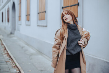 Fashion photo of a ginger woman walking on street with bouquet.