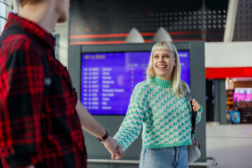 A happy girl is holding hands with her boyfriend at train station.