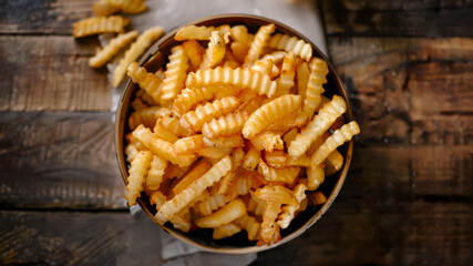 A top down image of an air fryer basket full of crinkle cut French fries. - obrazy, fototapety, plakaty