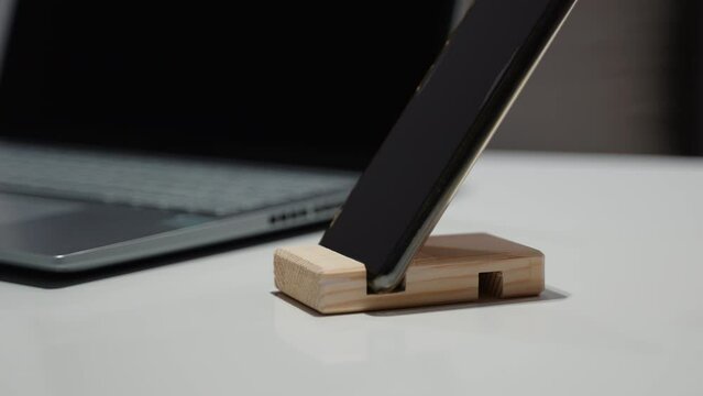 Women's hand takes phone from the wooden phone holder