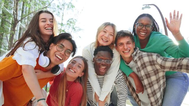 Big group of multiracial young student people smiling, gesturing and looking at camera. Happy internacional teenagers laughing. Cheerful friends enjoying their freedom. Classmates on friendly meeting