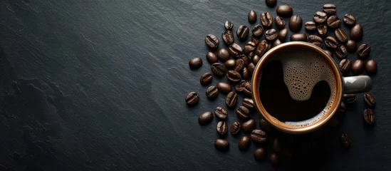 Poster A bold and beautiful cup of black coffee is placed on a rustic black background, creating a captivating blend of elegance as it is surrounded by coffee beans. © AkuAku
