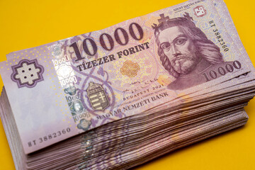 Hungarian large-denomination banknotes, (forint) paper money, HUF 10,000 banknotes spread out on a yellow table, background close-up. Europe Hungary.