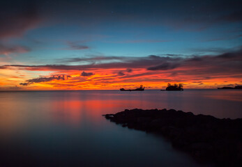 An ocean view of the sunset from Agat, Guam with a breakwater in the foreground
