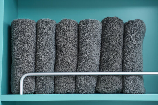 Folded gray towels in the closet close-up front view, space organization concept.