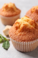 Delicious sweet muffins on light grey textured table, closeup