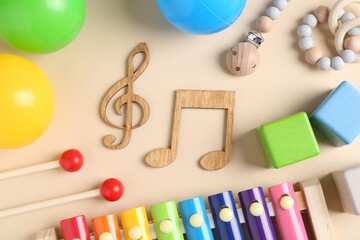 Baby song concept. Wooden notes, kids xylophone and toys on beige background, flat lay