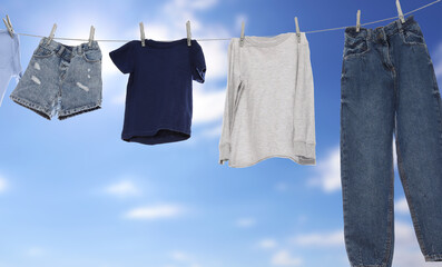 Different clothes drying on washing line against blue sky, banner design