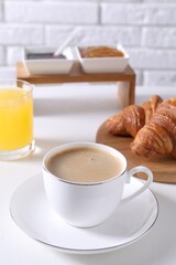 Fresh croissants and coffee on white table. Tasty breakfast
