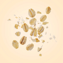 Rolled oat flakes falling on beige background