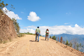 Senior hiking couple walking along a rural Andean road up a mountain in Santander, Colombia.