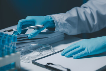 A scientist is writing down the results of an experiment in a report card, A laboratory full of scientific equipment for experiments, Many test tubes were analyzed by experts.