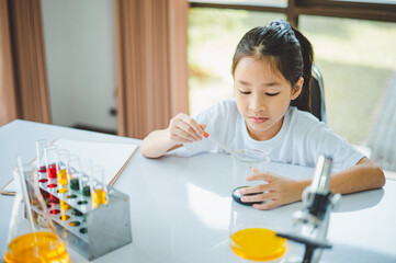 little scientist looking through a microscope and test tubes filled with chemicals for learning about science and experiments.