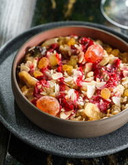 Morning granola breakfast with raisins, cranberries, banana in bowl on marble table with drinks. Bowl of oatmeal porridge, Healthy breakfast food, diet, top view