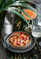 Morning granola breakfast with raisins, cranberries, banana in bowl on marble table with drinks. Bowl of oatmeal porridge, Healthy breakfast food, diet, top view