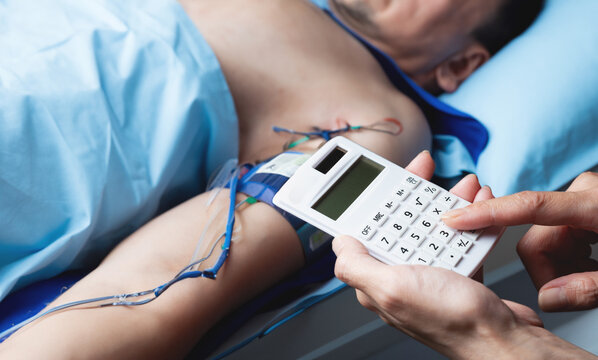 Close up of hand holding calculator on background of patient lying in hospital