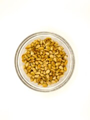Overhead pine nuts in a small glass bowl, isolated on white