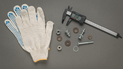 Gloves, a fastening tool and an electronic vernier caliper on a gray background.