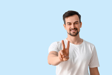 Handsome man showing victory gesture on blue background