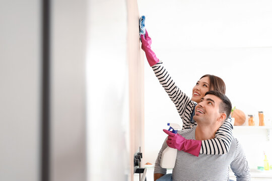 Happy young couple cleaning in kitchen - Powered by Adobe