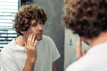 Caucasian young man washing and clean face with facial foam and water. 