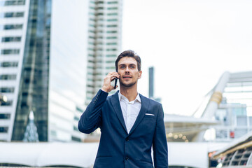 Caucasian young businessman talk on smartphone while walk in the city. 