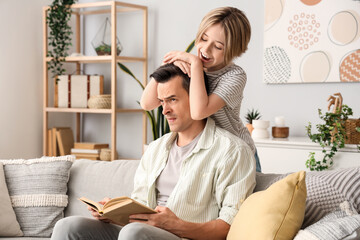 Young man with book stressed of his naughty little son at home