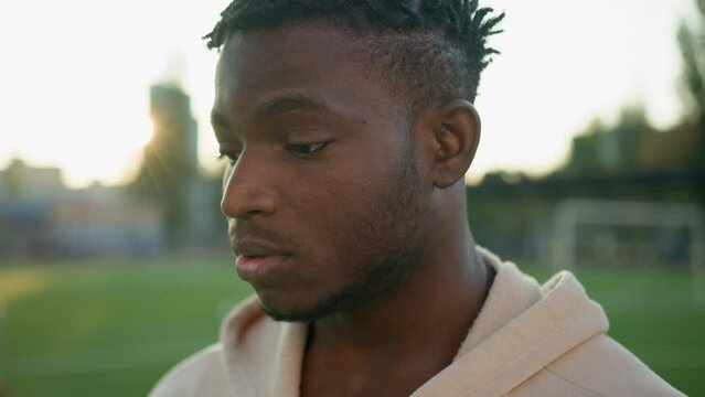 Tired African American man ethnic guy in sunlight sunny outdoors relax after sport exercise on city stadium hard breathe fatigue close up young male exhausted unhappy sportsman resting end of workout