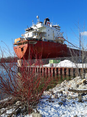 A large ship lies at winter dock on a lake.  