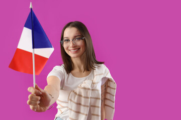 Beautiful young woman with flag of France on purple background